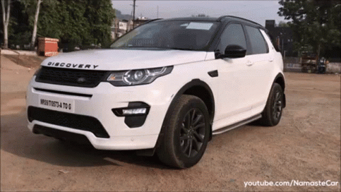 A White Discovery Is Parked On A Dirt Road GIF