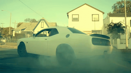 A White Dodge Challenger Is Driving Down The Street GIF
