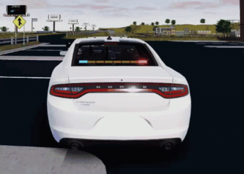 A White Dodge Charger Is Driving Down The Road GIF
