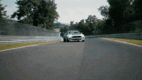 A White Ford Mustang Is Driving Down A Track GIF