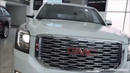 A White Gmc Suv Is In A Showroom GIF