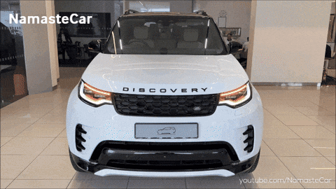 A White Land Rover Discovery Is Shown In A Showroom GIF