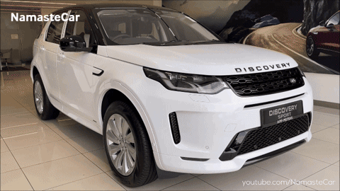 A White Land Rover Discovery Sport Is On Display In A Showroom GIF