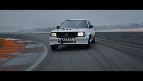 A White Opel Car Is Driving Down A Track GIF