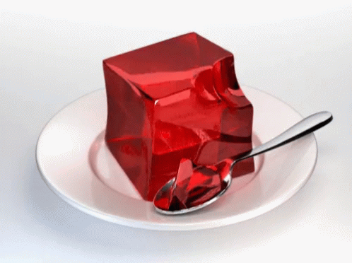 A White Plate Topped With A Piece Of Red Jelly And A Spoon GIF