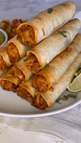 A White Plate Topped With A Stack Of Tacos And Lime Wedges GIF