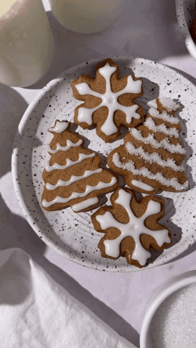 A White Plate Topped With Gingerbread Cookies In The Shapes Of A Tree Snowflake And Snowflake GIF