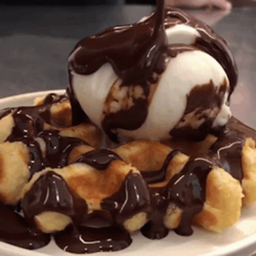 A White Plate Topped With Waffles And Ice Cream With Chocolate Sauce GIF