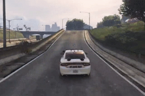 A White Police Car Is Driving Down A Road GIF