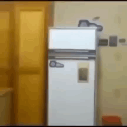 A White Refrigerator Is Sitting In A Room Next To A Yellow Door GIF