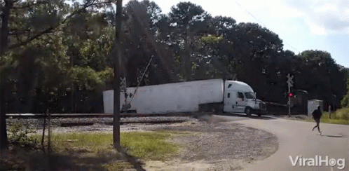 A White Semi Truck Is Crossing A Railroad Crossing With A Viralhog Logo In The Background GIF