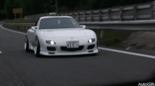A White Sports Car Is Driving Down A Road With A License Plate That Says Esc GIF