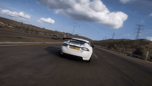 A White Sports Car Is Driving Down A Road With A License Plate That Says Tmz - Xm GIF