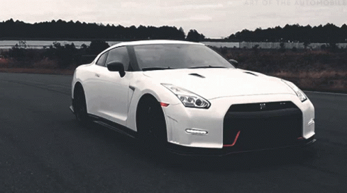 A White Sports Car Is Driving Down A Road With The Words Art Of The Automobile Visible In The Background GIF