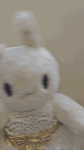 a white stuffed bunny with a gold bow on its neck