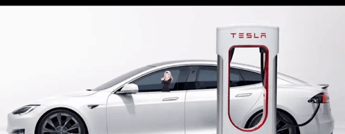 A White Tesla Is Being Charged At A Charging Station GIF