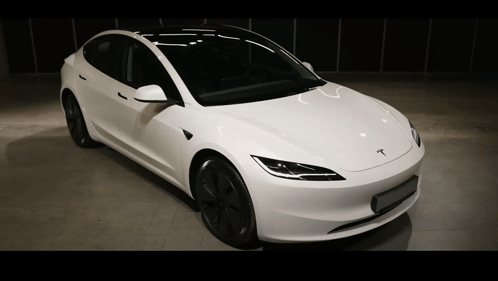 A White Tesla Is Parked In A Dark Room GIF