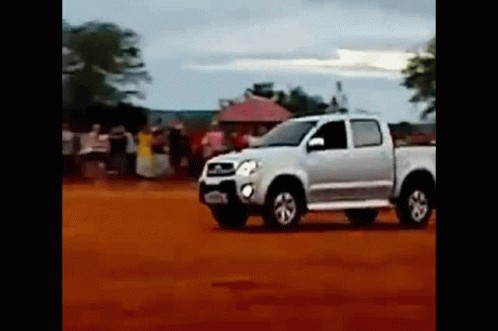 A White Truck Is Driving On A Dirt Road In A Field . GIF