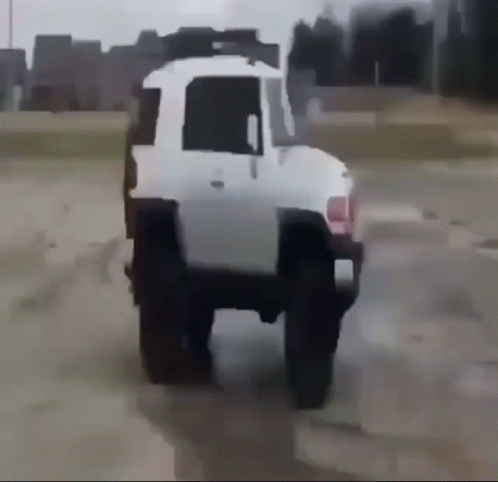 A White Truck Is Driving Through A Dirt Field GIF