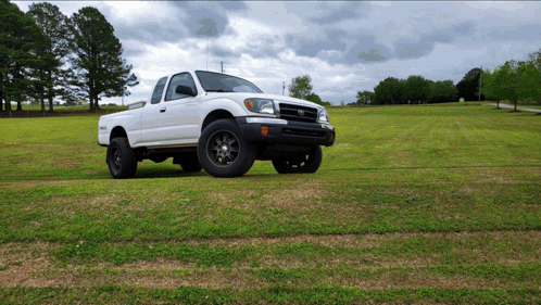 A White Truck Is Parked In A Grassy Field On A Cloudy Day GIF