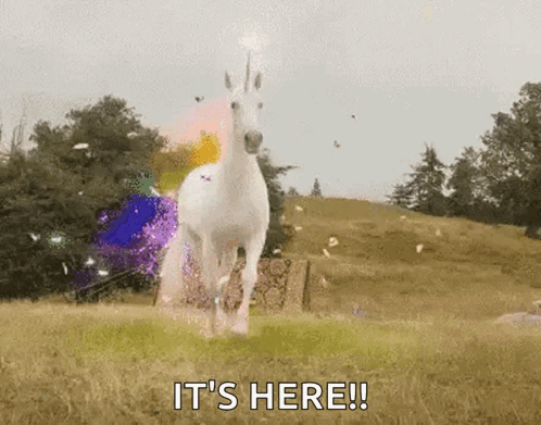 A White Unicorn Is Running In A Field With The Words It 'S Here Written Below It . GIF