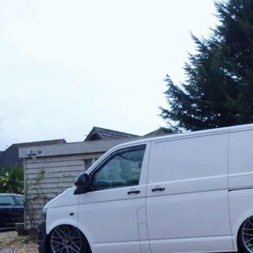 A White Van Is Parked In Front Of A Building With A Cross On It GIF