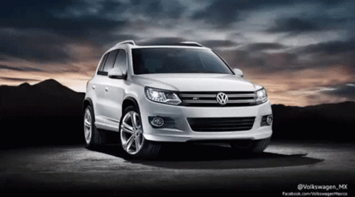 A White Volkswagen Car Is Parked In Front Of A Mountain GIF