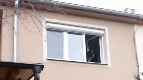 A Window On The Side Of A House With A White Shutter On It GIF
