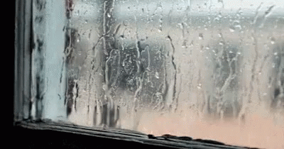 A Window With Rain Drops On It And A Person Looking Out . GIF