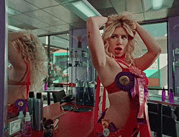 A Woman Adjusts Her Hair In Front Of A Mirror In A Beauty Salon GIF