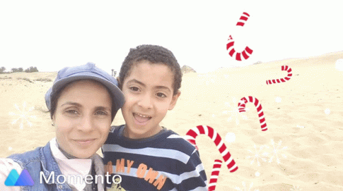 A Woman And A Boy Are Posing For A Picture With Candy Canes And Snowflakes In The Background GIF