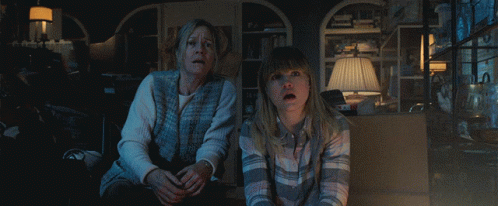 A Woman And A Girl Are Sitting In A Dark Room Looking At Something GIF