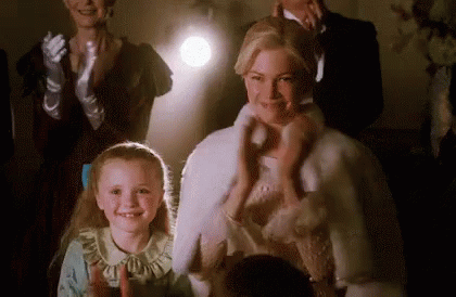 A Woman And A Little Girl Are Standing In Front Of A Crowd . GIF