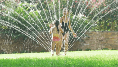 A Woman And Child Are Playing With A Sprinkler And The Number 624173610 Is On The Bottom GIF