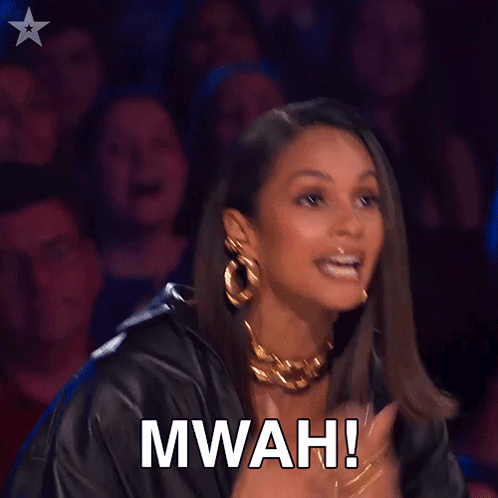 A Woman Applauds In Front Of A Crowd With The Words Mwah Written On Her Face GIF