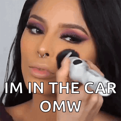 A Woman Applying Makeup With The Words Im In The Car Omw GIF