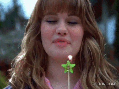 A Woman Blowing Out A Candle With A Star On It GIF