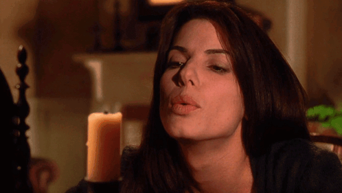 a woman blows a kiss in front of a lit candle