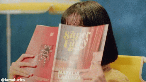 A Woman Covering Her Face With A Magazine Titled Super Lucky GIF