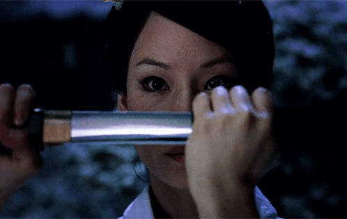 A Woman Covering Her Face With A Sword GIF