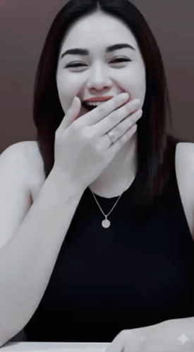a woman covering her mouth with her hand while wearing a necklace and a ring