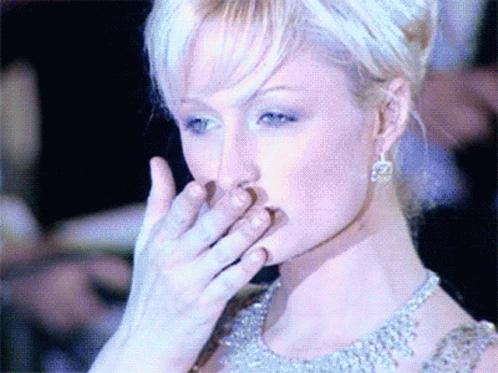 A Woman Covering Her Mouth With Her Hand While Wearing Earrings GIF