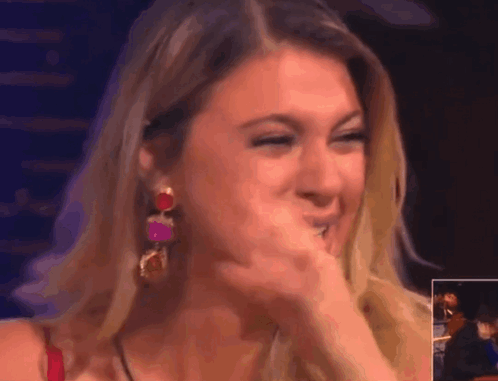 A Woman Covering Her Mouth With Her Hand While Wearing Earrings GIF