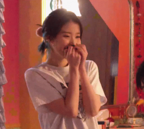 a woman covering her mouth with her hands in front of a mirror