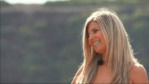A Woman Covering Her Mouth With Her Hands While Standing On A Hill GIF