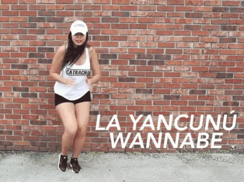 A Woman Dancing In Front Of A Brick Wall That Says La Yancunu Wannabe On It GIF