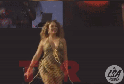 A Woman Dancing In Front Of A Lsa Audience Logo GIF