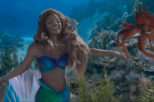 A Woman Dressed As A Mermaid Is Holding A Crab In Her Hands GIF