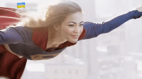 A Woman Dressed As Superman Is Flying Through The Air . GIF
