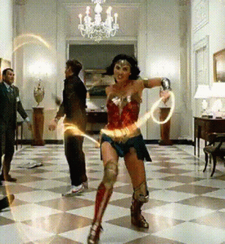 A Woman Dressed As Wonder Woman Is Dancing In A Room GIF